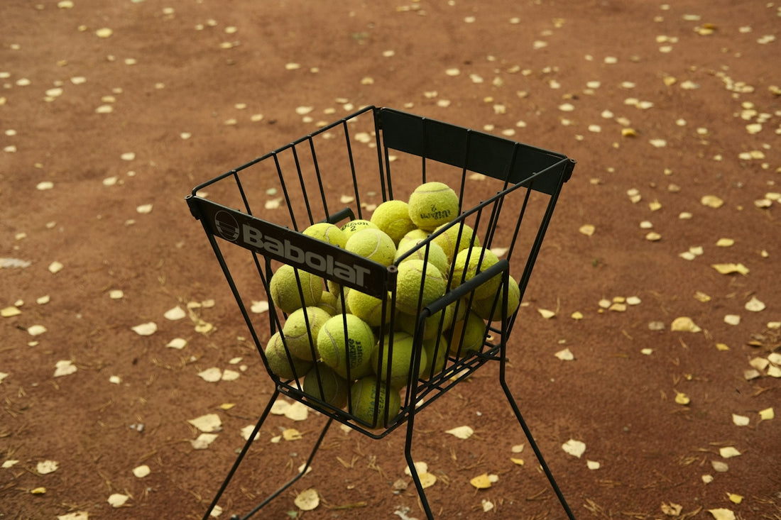 a basket of tennis balls sitting on top of a metal stand
