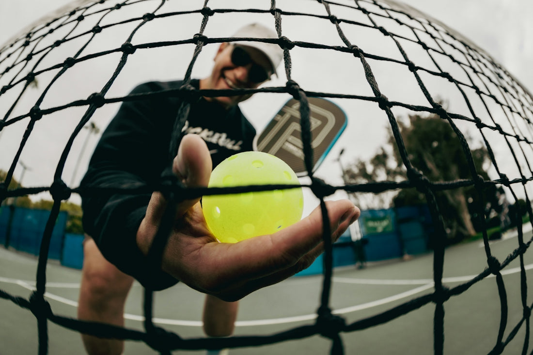 Pickleball player holds a ball with the net in view