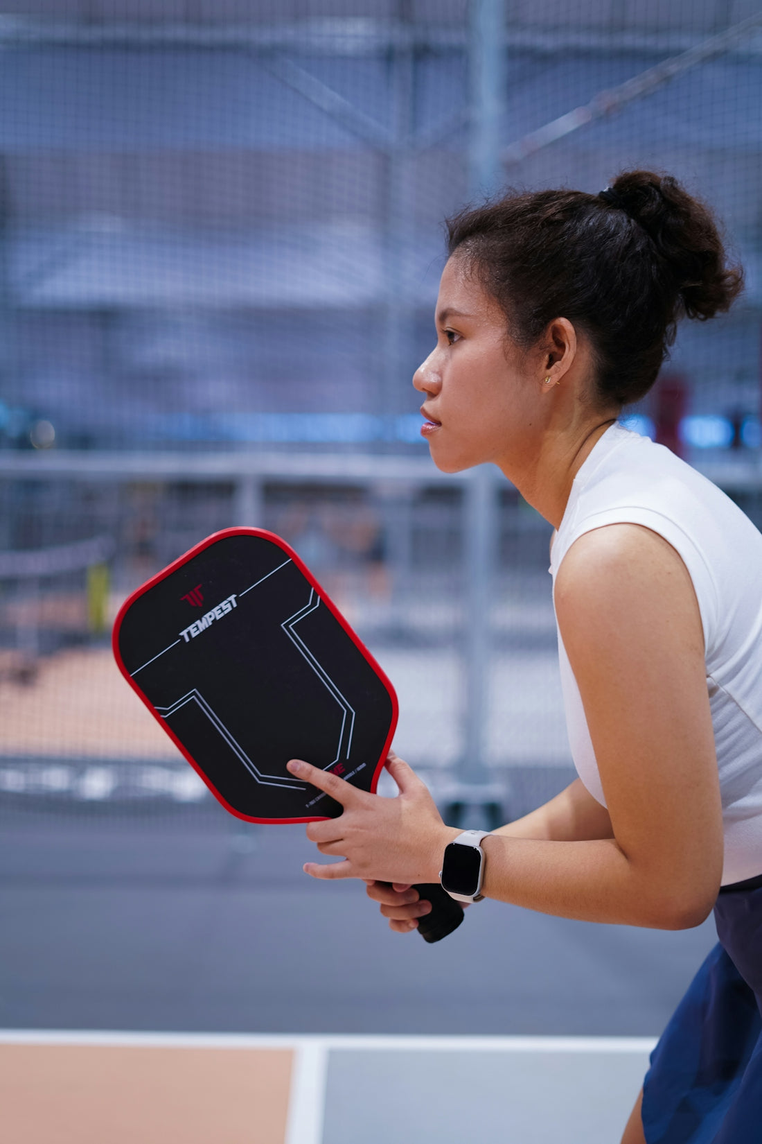 A young woman holds a pickleball paddle, ready to play